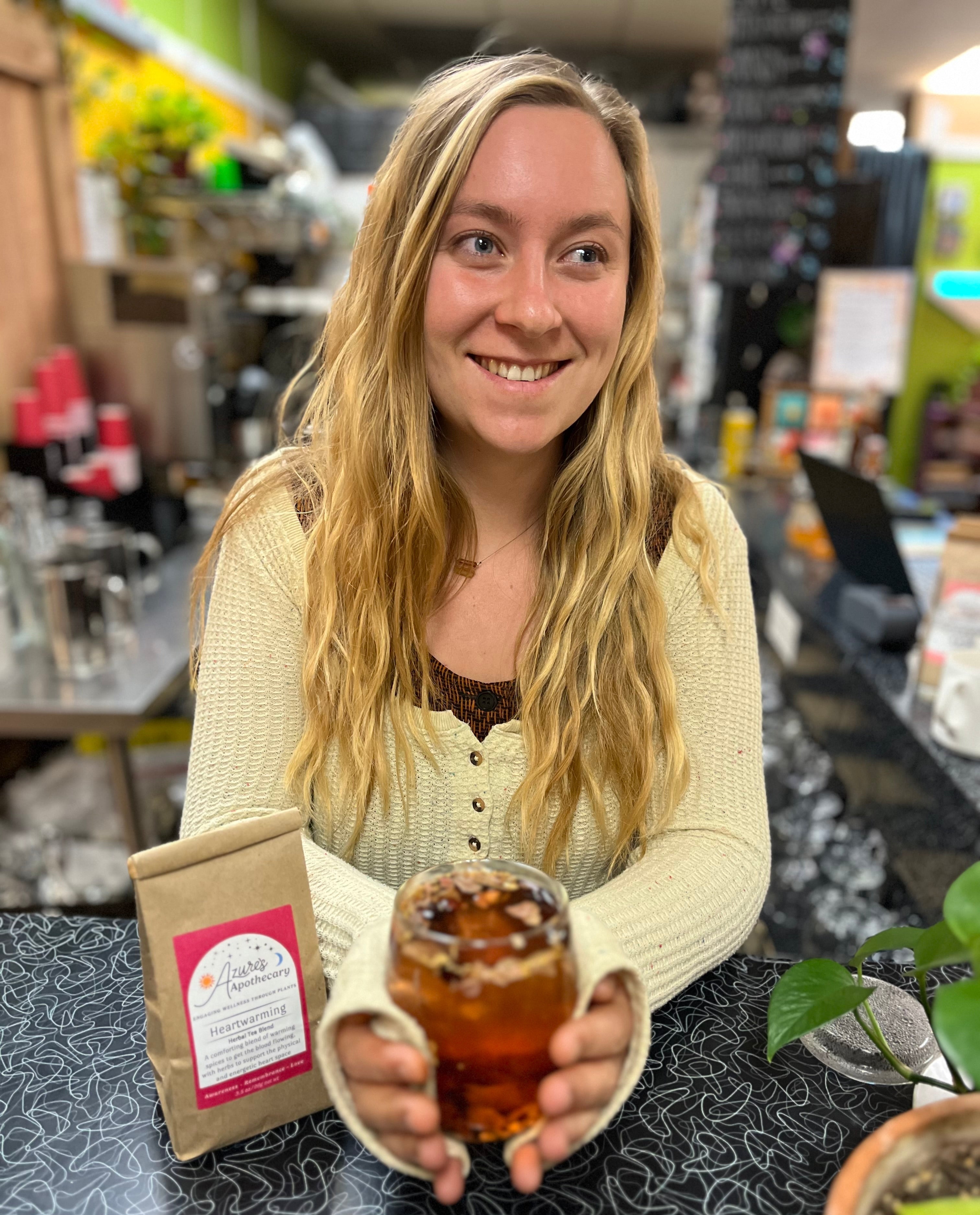 Woman holding a glass of loose leaf tea in a cafe 